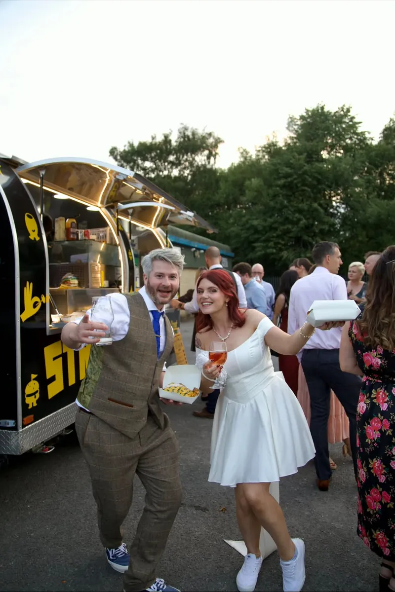 A bride and groom outside the STREET van with gyros boxes and drinks